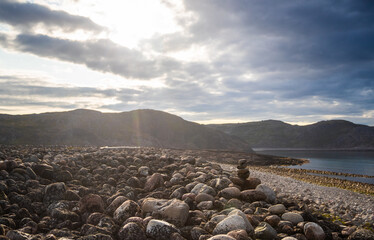 The rocky shoreline features smooth stones at Dragon Eggs beach arranged artistically, with a...