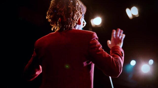 Host of event speaking on stage, rear view of black man performing for audience. Life coach or startup owner presenting ideas, emotional stand-up comedian talking comical monologues in concert hall