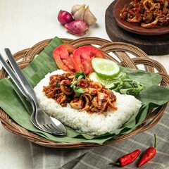 Indonesian nasi bakar, grilled rice, A serving of fragrant rice topped with spicy seafood, accompanied by fresh cucumber, tomato, and chilies, beautifully presented on banana leaves