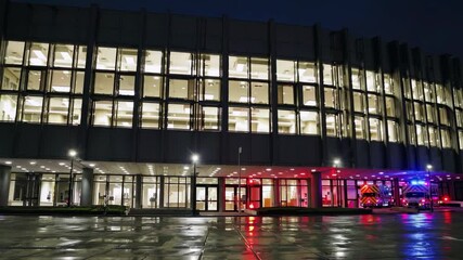 Emergency response at night in urban center with flashing lights and wet pavement