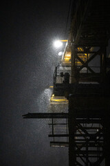 snow under the light of a construction crane at night