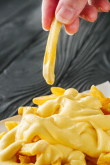 delicious crispy golden french fries with cheese on a black wooden rustic background