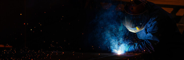 A man in a blue jacket is welding long horizontal photo