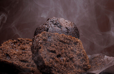 Cut chocolate muffin and whole muffin on brown background. Steam comes out from fresh chocolate muffin.