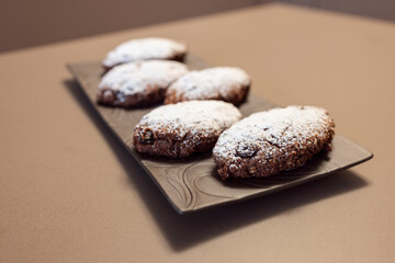 Rustic Pan dei Morti cookies, dusted with powdered sugar and rich in dried fruits, cocoa, and spices, displayed on a decorative plate
