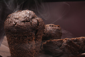 Cut chocolate muffin and whole muffin on brown background. Steam comes out from fresh chocolate muffin.