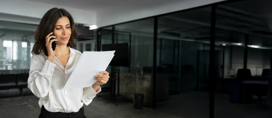 Middle aged businesswoman having business phone call with partners, clients, looking at documents....
