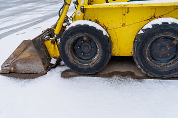 Yellow old and cold wheel skid loader construction machinery. Cold winter construction project...