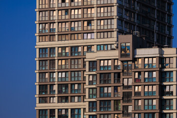 Obraz premium Modern buildings, walls and windows, reflections and sun rays. City view on a sunny day. 