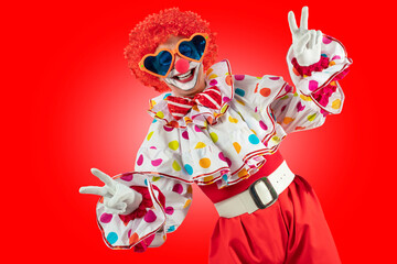 Funny clown in the circus, man entertainer as Joker in a suit and wig, with clown whiteface makeup....