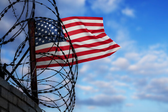 Wall with barbed wire and US flag. Concept of problems with freedom, deportation, citizenship, crisis on the border