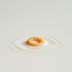 A single cereal loop floating above a milk ripple