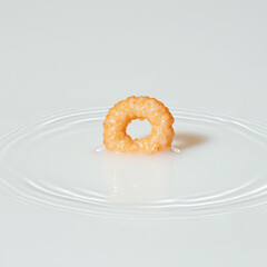 A single cereal loop floating above a milk ripple