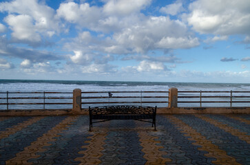 bench facing a sea and a cloudy sky