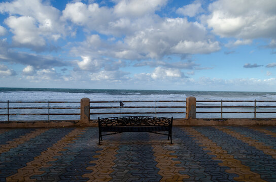 bench facing a sea and a cloudy sky