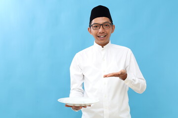 Happy asian muslim man presenting an empty plate. Ramadan concept