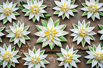 Obraz premium Intricate paper flowers, white and yellow, arranged on a stone surface.