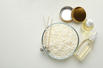 Soy wax and other supplies for making candles on white table, flat lay. Space for text
