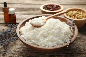 Soy wax in bowl and other different ingredients for making candles on wooden table, closeup