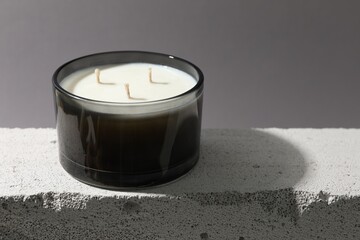 Soy wax candle on concrete block against gray background, space for text