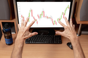 Nervous male trader lost his investments. Man at home trading, charts on monitor, excited and nervous