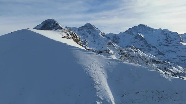 Eiger North Face, Monch and Jungfrau Mountains in Winter. Swiss Alps. Switzerland. Aerial View. Moving Forward and Upwards over Snowy Mannlichen Top. Reveal Shot. Anti-Avalanche Structure, Barrier