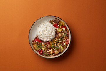 top shot on blue background black salad plate with Chinese rice and veal with vegetables sprinkled with nuts Asian cuisine healthy eating