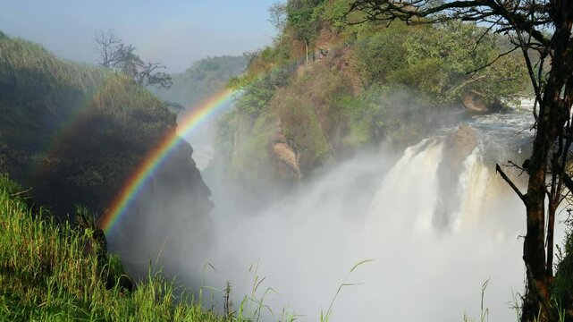 Majestic Murchison Falls in Uganda with a rainbow coming from the spray of the Nile River.