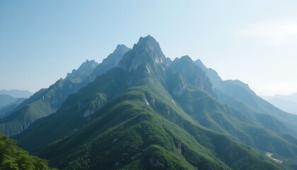A majestic mountain range with lush green peaks, standing tall under a soft blue sky, creating a tranquil nature scene.