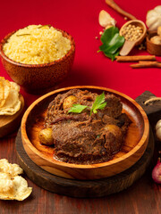 Indonesian beef rendang, A flavorful beef dish is presented alongside a bowl of aromatic rice and crispy snacks, creating an inviting dining experience