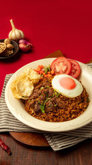 Indonesian rendang fried rice, A delicious plate of seasoned rice topped with tender beef, a fried egg, and fresh tomato slices, surrounded by garlic and spices
