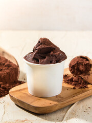 Indulge in creamy chocolate gelato displayed in a cup, garnished with cocoa powder and surrounded by chocolate pieces