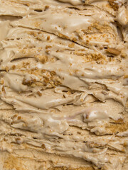 A rich caramel biscuits ice cream gelato features smooth swirls and crunchy cookie crumbs, inviting a delightful taste experience on a sunny day