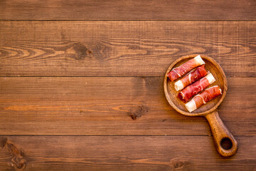 Prosciutto - rolls of ham on wooden cutting board, top view.