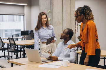 Business colleagues working together, sharing ideas and using technology in a bright and collaborative workspace