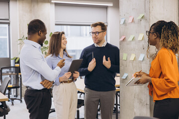 Business team discussing new project ideas using sticky notes on a wall in a modern office