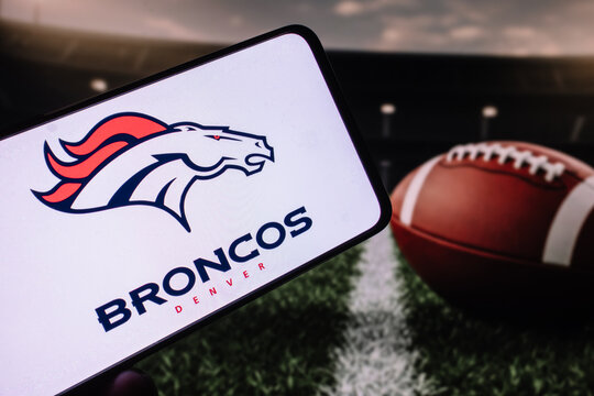 London, UK, 02.04.2025: Denver Broncos american football team logo on phone screen with ball on the field background