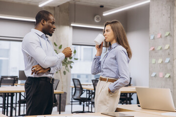 Multi ethnic colleagues enjoying a coffee break, chatting and relaxing in a modern office environment