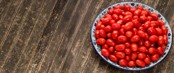 Fresh cherry tomatoes on a plate. Rustic wooden background. Banner with space for text.