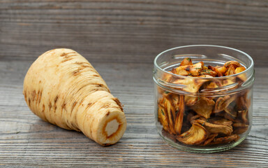 Parsnip chips in a glass jar and raw parsnip root.