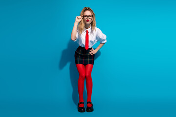 Young stylish girl in fashionable outfit posing with vivid blue background emphasizing bold red...