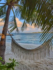 A relaxing hammock swings by the ocean on Maafushi Island, Maldives, offering a peaceful retreat