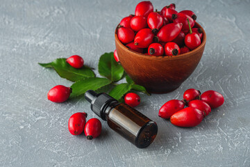 fresh red rose hips on a stone background essential oil