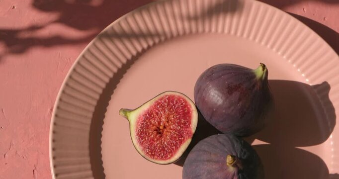 Plate with ripe figs fruit on the mediterranean pink terracotta color plaster background with leaves shadows.