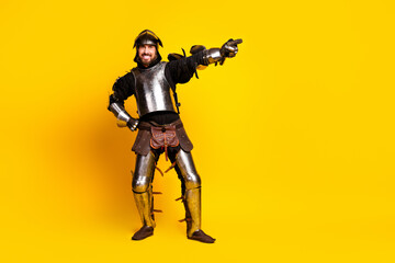 Cheerful man in medieval knight armor posing on vibrant yellow background