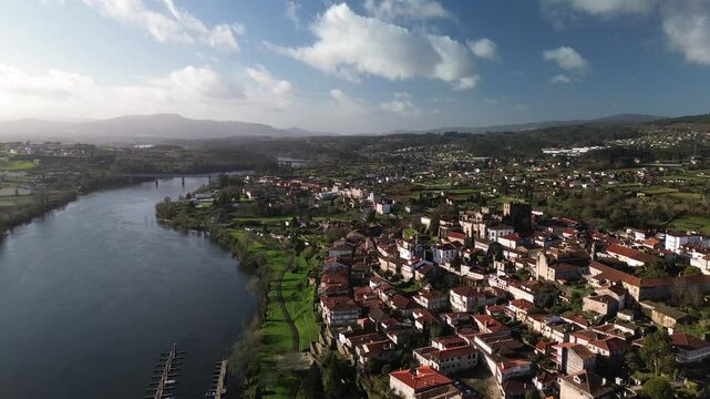 Aerial view of Tui, featuring its historic cathedral overlooking the calm Mi&ntilde;o River, the natural border between Spain and Portugal. Tui-Valen&ccedil;a International Bridge and marina are visible.