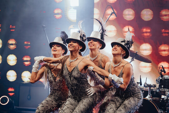 A glamorous cabaret performance featuring dancers in elegant feathered hats and sparkling costumes, captivating the audience with high-energy choreography and dazzling stage lighting