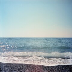 Fototapeta premium Tranquil ocean waves lapping against a pebble beach under a clear sky