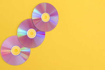 Three colourful compact discs on a yellow background