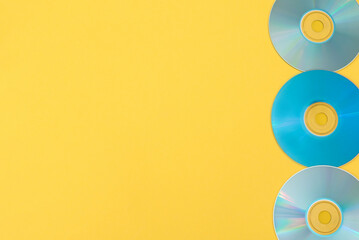 Line of three blue cds on yellow background with copy space